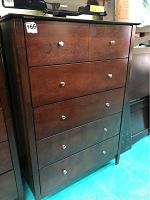 Front view of the wooden chest of drawers showing five drawers and metal knobs.