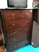 Front view of closed wooden chest of drawers with six drawers and metal knobs, dark brown finish.