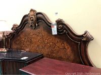 Full view of the tall ornate headboard showing the wood grain, carved details and shape of the piece.