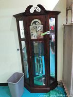 Full view of grandfather clock showing wooden case, bonnet top and base
