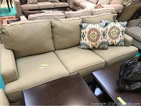 Front view of three-seat beige sofa with two patterned throw pillows