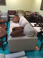 Side view of the beige upholstered couch with seat and back cushions plus three brown throw pillows.
