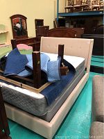 Complete Casana queen upholstered bed frame stacked with wooden legs on mattress and box spring not included.