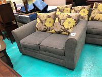 Front view of grey loveseat with floral pillows