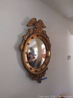Frontal view of vintage round mirror showing gold eagle atop ornate frame and convex glass.