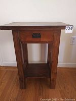 Front view of teak side table showing drawer with metal pull and lower shelf