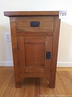 Front view of the teak side table showing the drawer and cabinet door with metal handles.