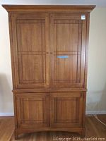 Front view of solid wood two-piece entertainment unit showing upper and lower cabinet doors.