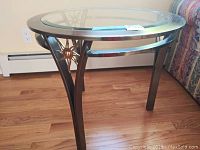 Side view of the oval metal end table showing the curved metal legs and sunburst design.