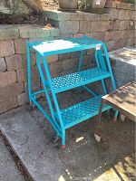 Three-step blue metal stool with perforated treads and casters