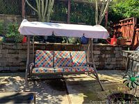 Full front view of three-seat swing under canopy on patio