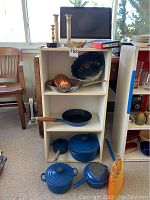 Full view of shelf with cookware on floor and accessories on top