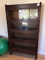 Full front view of four-tier bookcase showing glass-front doors and oak frame