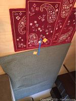 Large solid gray-green rectangular rug partially visible below red rugs