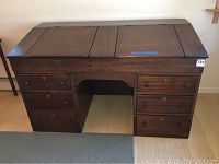 Full front view of vintage wooden desk showing drawers and three-panel top