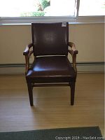 Front view of vintage wooden armchair with brown leather seat and backrest, showing the overall condition and design.