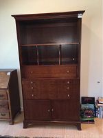Front view of tall wooden entertainment center showing open shelves, drawers, and cabinet doors.
