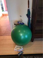 Photo showing green yoga ball, multiple boxes of Srixon golf balls, golf umbrella leaning against the wall, and a wall pump packed in plastic.