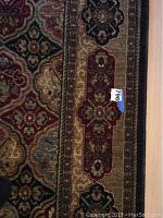 Close-up of border showing elongated floral medallion panel and size sticker