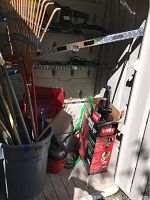 Photo showing the assortment of garden rakes, broom, shovel, and Toro boxed blower vacuum inside storage shed.