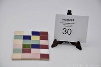 Close-up of a single colorful mosaic tile sheet with multiple colored square tiles and auction number.