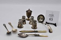 Photo showing all sterling silver items in the lot including ladle, salt and pepper shakers, spoons, knife, and lidded container