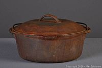 Rusty, aged cast iron dutch oven with lid, photographed on neutral background.