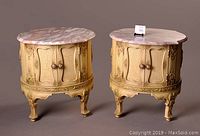 Photo of matched pair of carved wooden drum tables with pink marble tops, closed doors, showing ornate leg and carved detailing