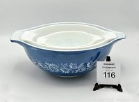 Large blue Pyrex Cinderella bowl with white daisy floral pattern and handles, photographed with auction lot number.