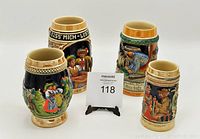 Four German-style beer steins arranged together showing different relief figures and characteristic traditional designs.