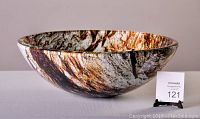 Glass vessel sink shown from side angle to highlight marble pattern and shape.