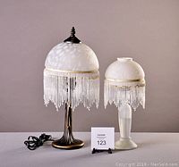 Photo of 2 beaded lamps, electric lamp on left and oil lamp on right, showing overall height and bead fringe detail