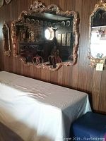 Large mirror and two side mirrors mounted on wood-paneled wall above furniture showing the set in situ.