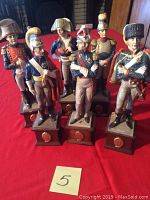 Front view of six Italian ceramic soldier figurines on wooden bases, showing detailed paint and uniforms.