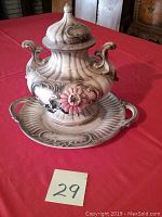 Full view of ceramic tureen with lid on matching platter showing ornate handles and pink flower decoration.