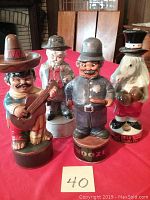 Photo of all four vintage ceramic liquor bottles arranged on red cloth background showing front and side views.