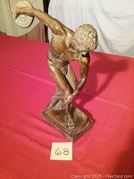 Front angled view showing the statue in detailed discus throw position, emphasizing the arm holding the discus and muscular anatomy.