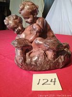 Front view of statue showing two cherubs in a playful pose on mushroom base with number 124 card in front.