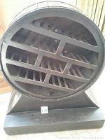 Front view of circular barrel shaped wood bottle holder showing multiple horizontal and angled slots designed to hold wine bottles.