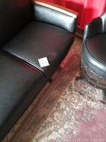 Close-up of black vinyl sofa seat showing minor puncture and wear