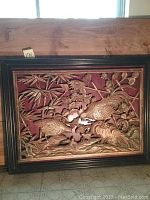 Frontal image of the rectangular carved wood relief art showing roosters, hen, and floral designs set in a black frame.