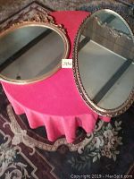 Photo showing both mirrors lying on a table with a red tablecloth and floral rug underneath.