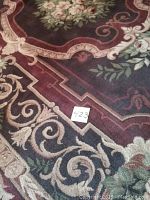 Close-up of floral medallion and scroll border with lot card