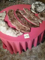 Five assorted fur collars in varying shades of white, brown, and beige laid out on a red tablecloth.