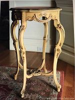 Front view of the yellow accent table showing cabriole legs, carved decorative details, and marquetry inlaid top.