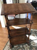 Full view of the wooden book stand display shelf showing the slanted top and three supporting shelves with turned wood posts and block feet.