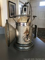 Front left angle showing the Delta logo, handle, and front reflector of vintage metal lantern.