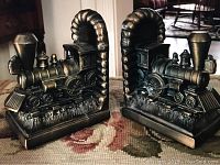 Pair of bronze-colored train engine bookends side by side showing full front and side views.