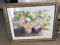 Close-up photo of the framed watercolor floral painting with gold and black frame, showing the delicate application of color and matting.