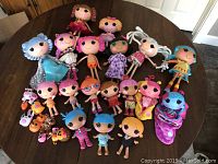 Full lot grouping showing all 18 LalaLoopsie dolls arranged on a table with some pets and accessories visible.